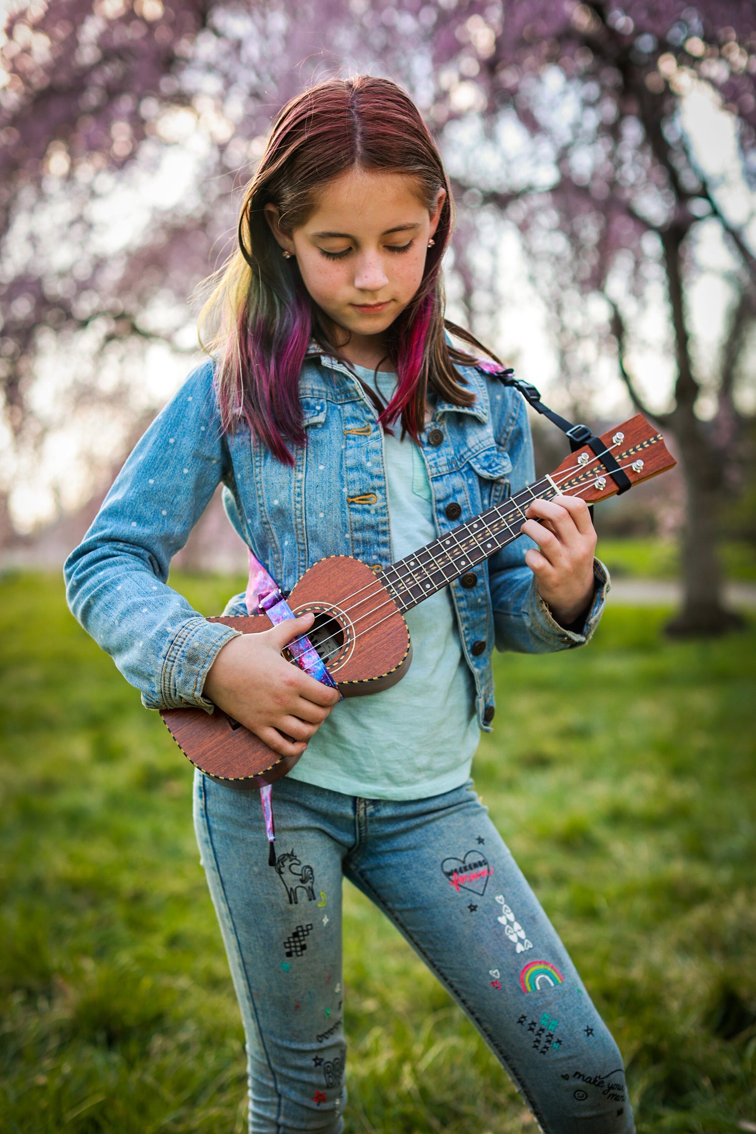 close up of a young girl playing the ukulele with The Hug Strap attached